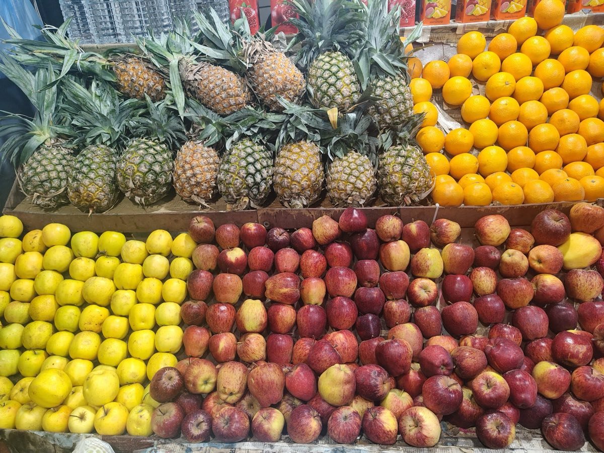 Pineapples, oranges and apples piled high on a fruit market stall